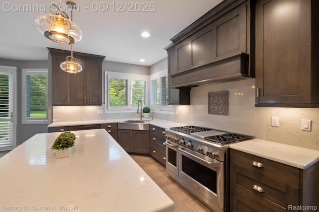 44251 Deep Hollow Cir, Northville, MI 48168 - kitchen with range with two ovens, a sink, dark brown cabinetry, custom exhaust hood, and pendant lighting