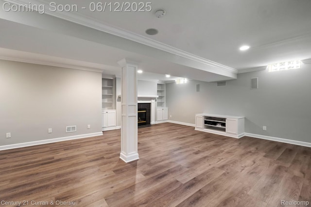 44251 Deep Hollow Cir, Northville, MI 48168 - below grade area with ornamental molding, a tiled fireplace, baseboards, wood finished floors, and built in features