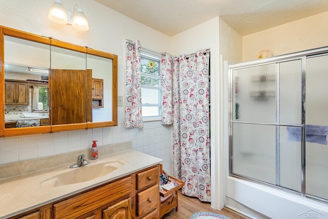 3077 Edson St, Coleman, MI 48618 - full bathroom with vanity, wood finished floors, tile walls, shower / bath combination with glass door, and a textured ceiling
