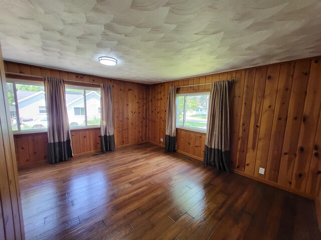 1010 S Pearce St, Owosso, MI 48867 - unfurnished room featuring wood-type flooring, baseboards, and wooden walls