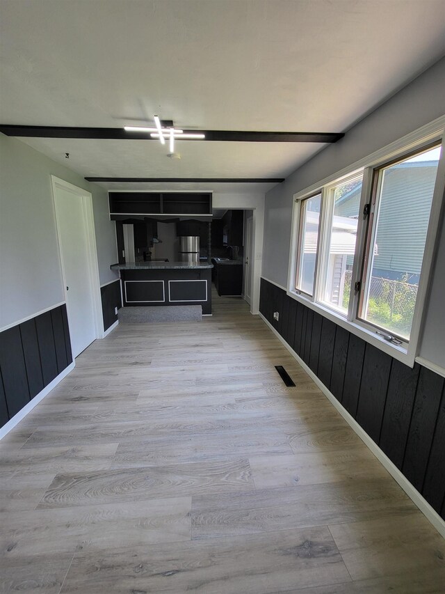 1010 S Pearce St, Owosso, MI 48867 - unfurnished living room featuring wainscoting, light wood-type flooring, and wood walls