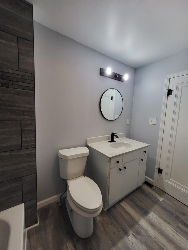 1010 S Pearce St, Owosso, MI 48867 - bathroom featuring vanity, wood finished floors, toilet, baseboards, and a tub