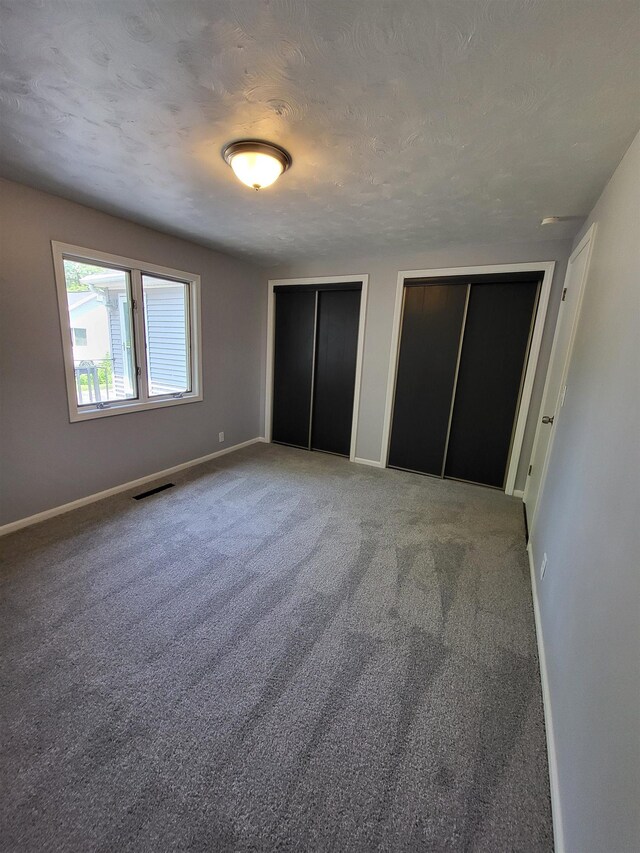 1010 S Pearce St, Owosso, MI 48867 - unfurnished bedroom with multiple closets, baseboards, and carpet