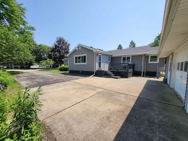 1010 S Pearce St, Owosso, MI 48867 - rear view of house with a wooden deck, driveway, and a patio