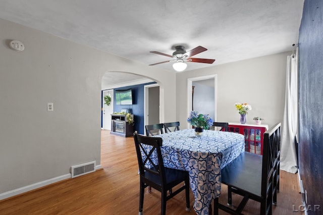 1104 Sunset Dr, Tecumseh, MI 49286 - dining room featuring arched walkways, a ceiling fan, wood finished floors, and baseboards