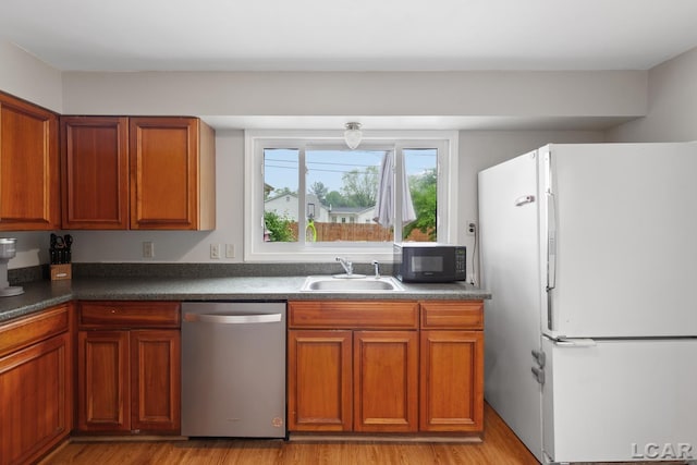1104 Sunset Dr, Tecumseh, MI 49286 - kitchen with dishwasher, freestanding refrigerator, black microwave, a sink, and dark countertops