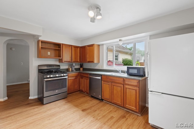 1104 Sunset Dr, Tecumseh, MI 49286 - kitchen with appliances with stainless steel finishes, arched walkways, light wood-type flooring, brown cabinets, and a sink