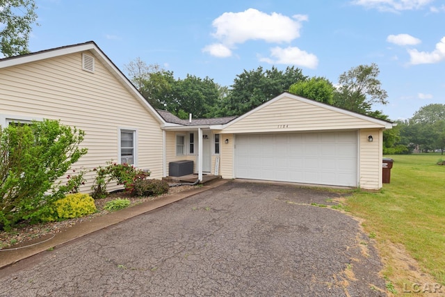 1104 Sunset Dr, Tecumseh, MI 49286 - ranch-style house featuring asphalt driveway, a front yard, and an attached garage