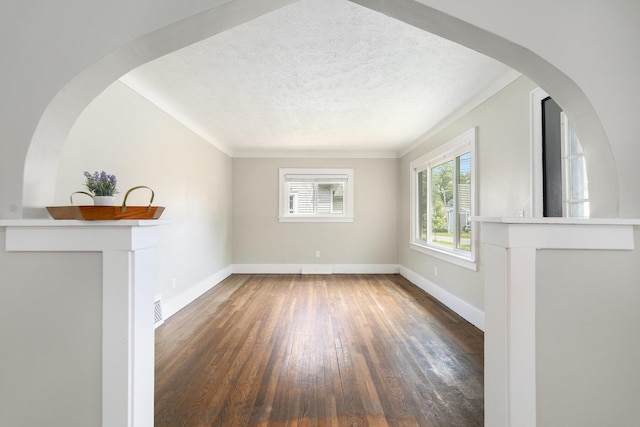 1831 Newark Ave SE, Grand Rapids, MI 49507 - unfurnished living room featuring hardwood / wood-style flooring, baseboards, a textured ceiling, ornamental molding, and arched walkways