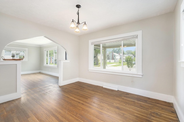 1831 Newark Ave SE, Grand Rapids, MI 49507 - unfurnished living room featuring wood finished floors, a chandelier, baseboards, and arched walkways