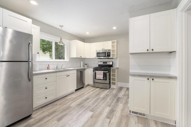 1831 Newark Ave SE, Grand Rapids, MI 49507 - kitchen featuring appliances with stainless steel finishes, light wood-style floors, light countertops, white cabinetry, and backsplash