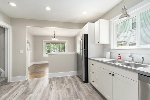 1831 Newark Ave SE, Grand Rapids, MI 49507 - kitchen featuring a sink, stainless steel appliances, white cabinetry, light wood-style flooring, and decorative light fixtures