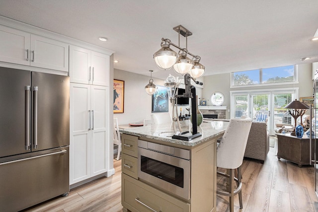 144 Dunkley Ave Unit 4, South Haven, MI 49090 - kitchen with stainless steel appliances, a kitchen bar, open floor plan, light wood finished floors, and light stone countertops