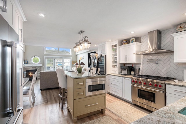 144 Dunkley Ave Unit 4, South Haven, MI 49090 - kitchen with high end appliances, wall chimney range hood, backsplash, open floor plan, and light stone counters
