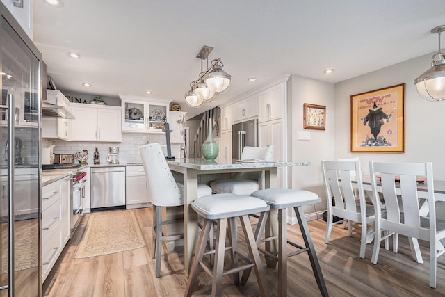 144 Dunkley Ave Unit 4, South Haven, MI 49090 - kitchen featuring high end appliances, light wood-style floors, white cabinetry, decorative backsplash, and recessed lighting