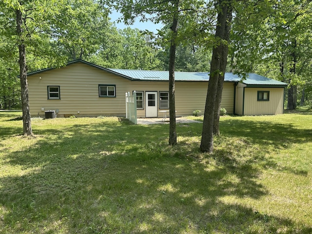 5649 W 76th St, Baldwin, MI 49304 - rear view of house with a yard, metal roof, central air condition unit, and view of wooded area