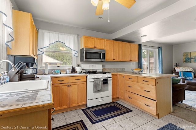 3128 Woodside Dr, Dearborn, MI 48124 - kitchen with white gas range oven, stainless steel microwave, a peninsula, tile counters, and a sink