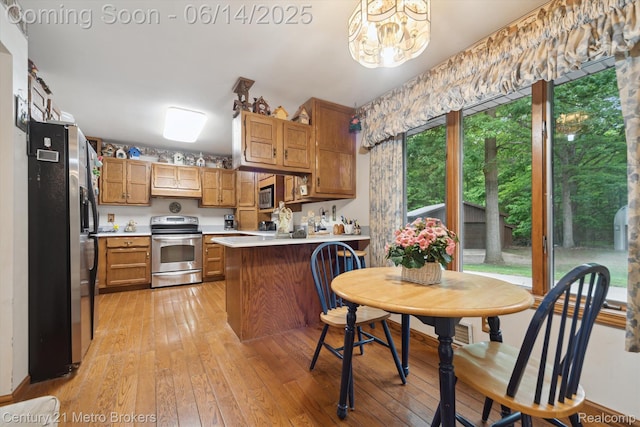 14210 W Burt Rd W, Chesaning, MI 48616 - kitchen featuring stainless steel appliances, a peninsula, light countertops, light wood-style floors, and a chandelier
