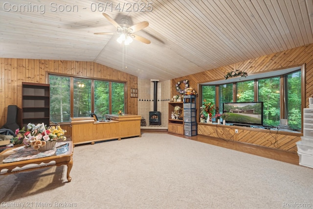 14210 W Burt Rd W, Chesaning, MI 48616 - living area with wood walls, a wood stove, vaulted ceiling, healthy amount of natural light, and a ceiling fan
