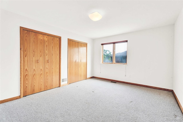 1870 Cass Lake Front Rd, Keego Harbor, MI 48320 - unfurnished bedroom featuring two closets, carpet floors, and baseboards