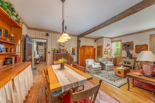 8425 Parshallville Rd, Fenton, MI 48430 - dining room featuring a wood stove, light wood-style floors, wooden walls, and beam ceiling