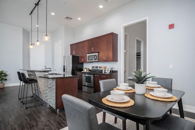 335 Bridge St NW Unit 500, Grand Rapids, MI 49504 - kitchen featuring appliances with stainless steel finishes, a kitchen bar, baseboards, dark wood-style floors, and recessed lighting