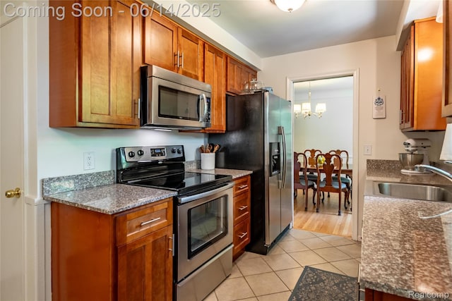 28441 Westerleigh Rd, Farmington, MI 48334 - kitchen with stainless steel appliances, a chandelier, light tile patterned flooring, and brown cabinets