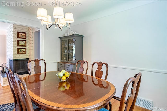 28441 Westerleigh Rd, Farmington, MI 48334 - dining area with a chandelier, light wood-type flooring, and a fireplace