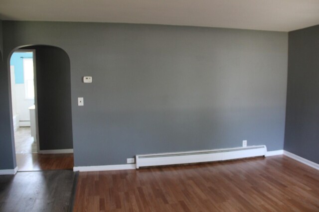 6994 E 34th Rd, Cadillac, MI 49601 - spare room with arched walkways, baseboard heating, wood finished floors, and baseboards