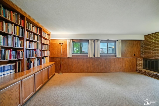 7658 Salter Ct, Temperance, MI 48182 - unfurnished room with wooden walls, light carpet, wall of books, a brick fireplace, and a textured ceiling