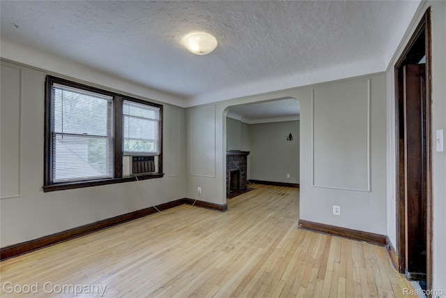 1722 W Farnum Ave, Royal Oak, MI 48067 - spare room with arched walkways, light wood finished floors, baseboards, a fireplace, and a textured ceiling