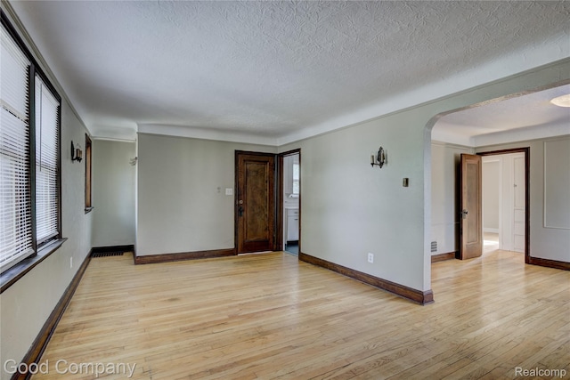 1722 W Farnum Ave, Royal Oak, MI 48067 - unfurnished room featuring light wood finished floors, a textured ceiling, arched walkways, and baseboards
