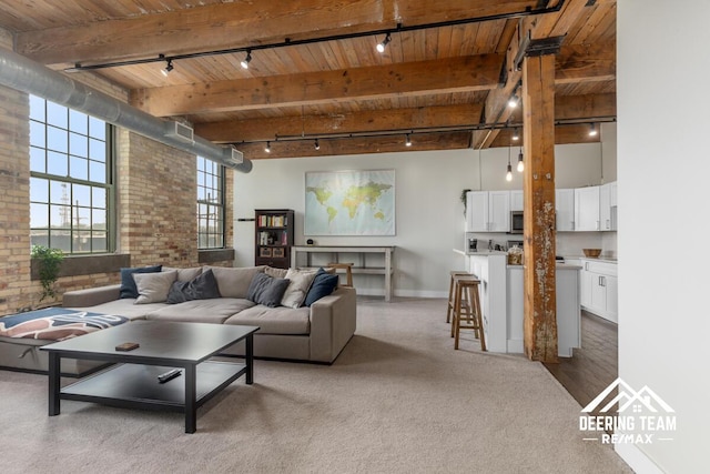940 Monroe Ave NW Unit 335, Grand Rapids, MI 49503 - carpeted living room with rail lighting, wooden ceiling with exposed beams, brick wall, a towering ceiling, and baseboards