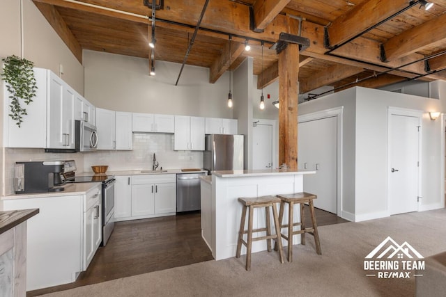 940 Monroe Ave NW Unit 335, Grand Rapids, MI 49503 - kitchen with stainless steel appliances, wooden ceiling with exposed beams, dark carpet, a breakfast bar, and a sink