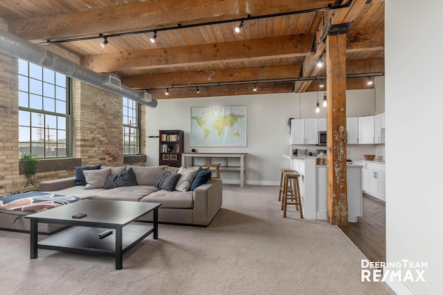 940 Monroe Ave NW Unit 335, Grand Rapids, MI 49503 - carpeted living room with track lighting, a wooden ceiling with exposed beams, brick wall, and a towering ceiling