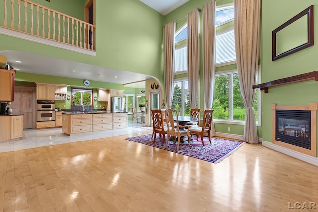 1269 Scott Ridge Dr, Adrian, MI 49221 - dining room featuring a high ceiling, arched walkways, light wood-style floors, a glass covered fireplace, and baseboards