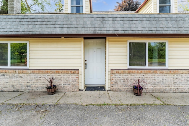 2006 W Rose Center Rd, Holly, MI 48442 - doorway to property featuring brick siding, a shingled roof, mansard roof, and a chimney