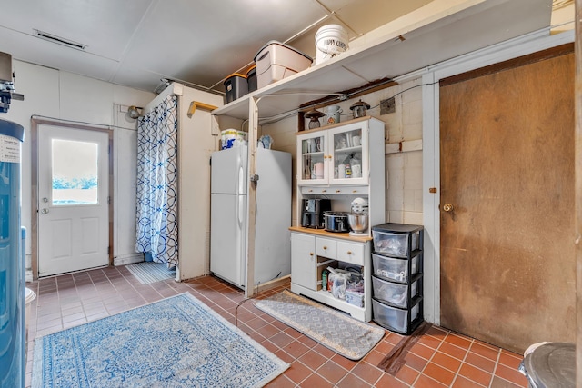 2006 W Rose Center Rd, Holly, MI 48442 - kitchen featuring freestanding refrigerator, tile patterned floors, glass insert cabinets, and white cabinets