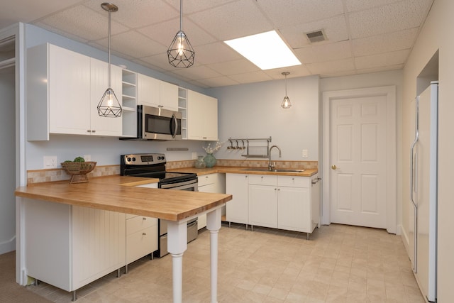 8562 W R Ave, Kalamazoo, MI 49009 - kitchen featuring stainless steel appliances, butcher block countertops, a sink, a paneled ceiling, and a peninsula