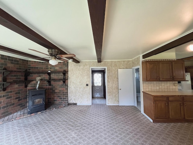 15522 Kimball Rd, Trufant, MI 49347 - kitchen with a wood stove, beam ceiling, a ceiling fan, carpet, and brown cabinetry