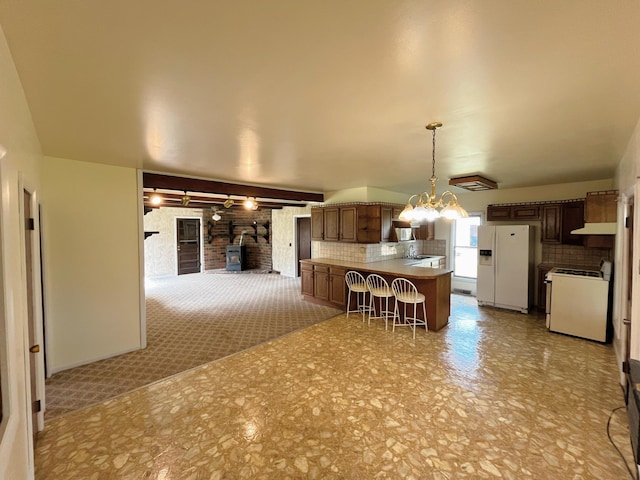 15522 Kimball Rd, Trufant, MI 49347 - kitchen with white appliances, a breakfast bar area, open floor plan, a chandelier, and decorative backsplash
