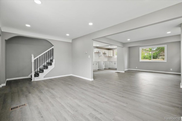 18287 Santa Rosa Dr, Dearborn, MI 48221 - unfurnished living room featuring stairway, wood finished floors, baseboards, recessed lighting, and arched walkways