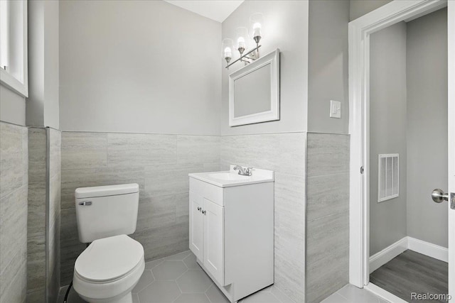 18287 Santa Rosa Dr, Dearborn, MI 48221 - bathroom featuring vanity, tile walls, toilet, a wainscoted wall, and tile patterned flooring