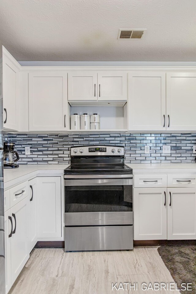 5869 Crosswinds Dr Unit 21, Norton Shores, MI 49444 - kitchen featuring electric stove, decorative backsplash, white cabinets, light countertops, and light wood-style floors