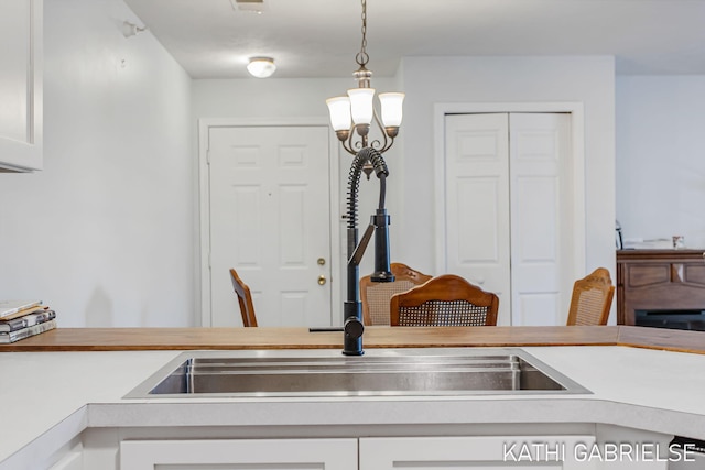 5869 Crosswinds Dr Unit 21, Norton Shores, MI 49444 - kitchen featuring a sink, light countertops, white cabinets, and decorative light fixtures