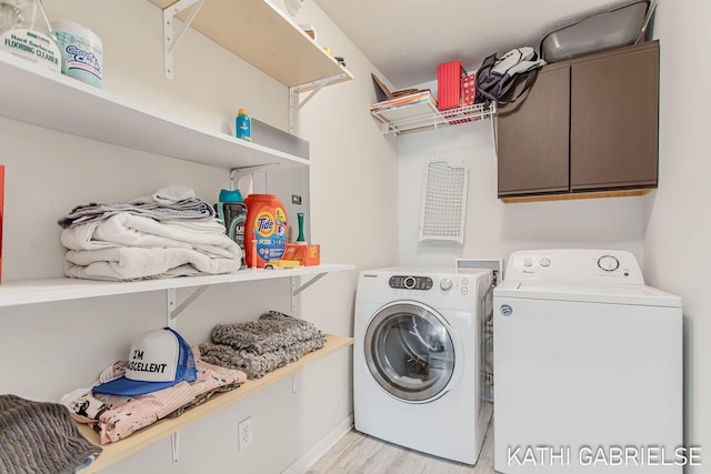 5869 Crosswinds Dr Unit 21, Norton Shores, MI 49444 - washroom featuring washing machine and dryer, cabinet space, and light wood-style flooring