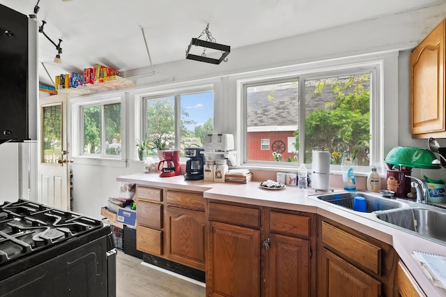 122 N Robinson St, Schoolcraft, MI 49087 - kitchen featuring black range with gas stovetop, light countertops, light wood finished floors, a sink, and brown cabinetry