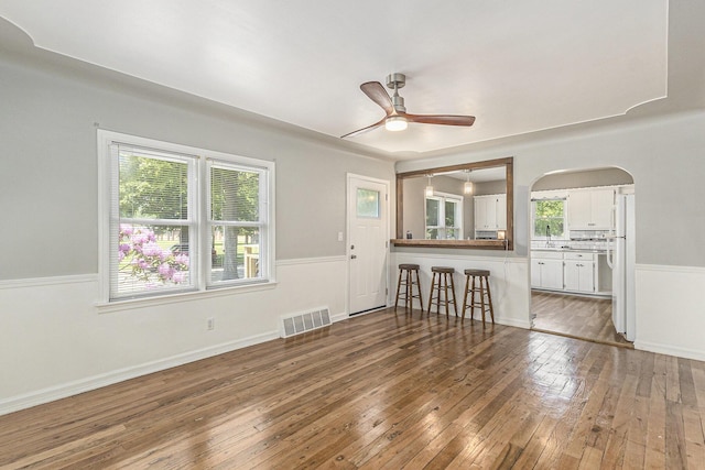 488 Roberts St, Muskegon, MI 49442 - unfurnished living room with ceiling fan, hardwood / wood-style floors, arched walkways, and a sink