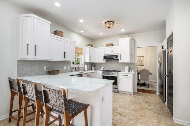 4844 Ontario Dr, Buchanan, MI 49107 - kitchen with stainless steel appliances, a peninsula, a kitchen breakfast bar, light stone counters, and decorative backsplash