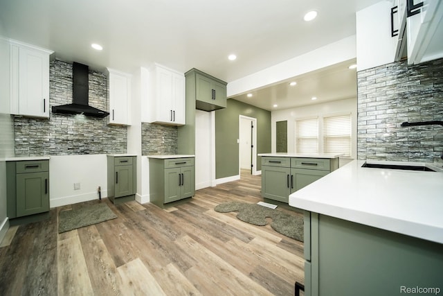 16240 Washburn St, Detroit, MI 48221 - kitchen with wall chimney exhaust hood, green cabinets, decorative backsplash, light wood-type flooring, and recessed lighting